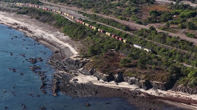 Train transporting shipping containers on the coastline 