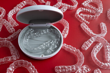 Transparent invisible dental aligners or braces aplicable for an orthodontic dental treatment. Invisible dental teeth brackets tooth aligners on blue background. Plastic braces dentistry retainers