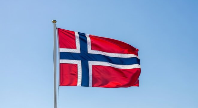Norwegian national flag waving against a clear blue sky on a flagpole. Symbol of national identity and patriotism for Norway Day celebration. - Powered by Adobe