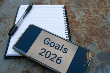 2026 goals template on a smartphone with a notebook and a pen.