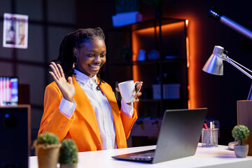 Smiling woman having friendly conversation with friends during teleconference meeting using laptop. Happy teenager doing greeting gesturing, having fun catching up with mates during online videocall