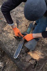 Man adjusting an electric chainsaw outdoors before work