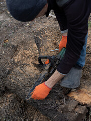 Man adjusting an electric chainsaw outdoors before work