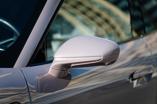 Vinnitsya Ukraine-15 July 2025:Pink Porsche Taycan side mirror close up with reflections of building