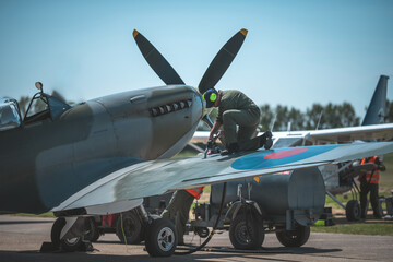 Aviation mechanic refueling a vintage fighter plane on a sunny day