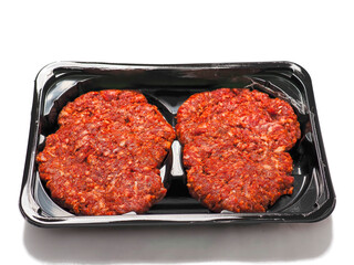Four fresh burgers on a black plastic tray on white background. Premium beef minced meat. Food supply chain and industry.