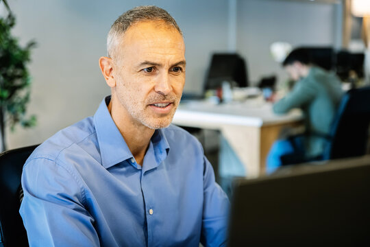 Mature businessman working on laptop at modern office. Focused professional man typing and concentrating on computer. Business and technology concept.