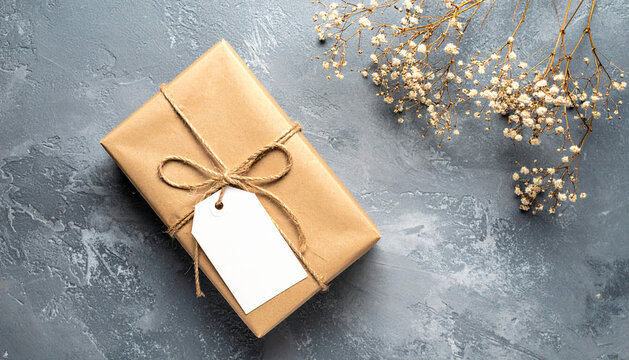 Beautifully Wrapped Gift Box with Blank Tag and Delicate Flowers on a Textured Surface