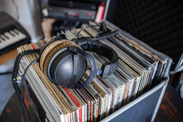 Retro headphones resting on a crate full of vinyl records in a home studio.