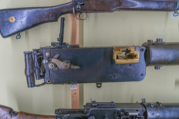 Vintage firearm collection displayed on wooden mounts or racks, arranged horizontally, with various...