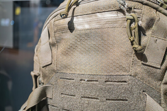 A camouflage backpack, possibly of military origin, displayed in a clear glass case against an unknown background The backpack features multiple compartments and reinforced edges, with a distinctive