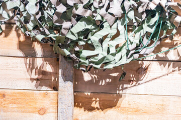 Wall-mounted, glossy, green, sunburst pattern artificial plant on wooden plank against rustic wood...