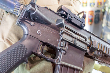 Close-up of a modern tactical rifle with collapsible stock and adjustable grip, featuring a...