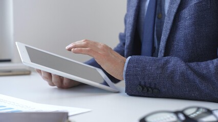 Businessman is using a digital tablet to analyze financial data, working with modern technology in the office for strategic corporate decision making and workflow optimization. Business people concept
