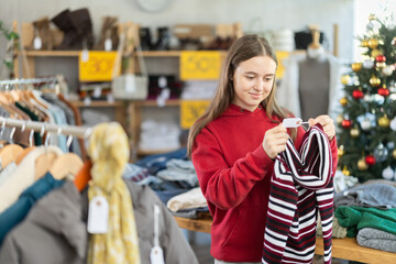 Teenage girl chooses a sweater in a fashion boutique.