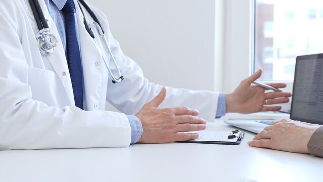 Adult doctor gesturing with hands while explaining diagnosis to patient during medical consultation in hospital office, healthcare and medical concept. Medicine concept