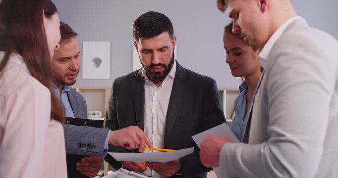 Focused business people with colleague handle paperwork during office meeting, emphasizing financial accounting and teamwork collaboration in a professional setting with attention and focus.