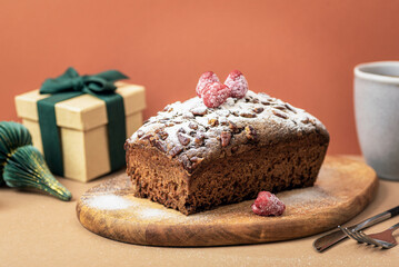 Chocolate Christmas cake with raspberries and sugar powder on wooden board. Closeup