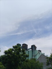 Industrial silos and storage tanks with trees under clear sky