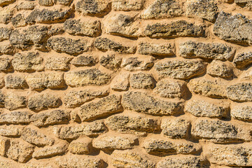 Ancient brick windmill in a Central European village, featuring weathered brown and beige bricks with no visible mortar, natural stone texture, uneven lighting casting soft shadows