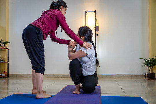 Yoga instructor guiding woman in balancing pose
