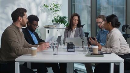 Multinational diversity Caucasian Indian team businesswomen businessmen business company men women briefing colleagues discuss project plan strategy in office sharing papers documents meeting partners