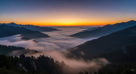 Dramatic sunset view over mountain range with clouds in the valleys