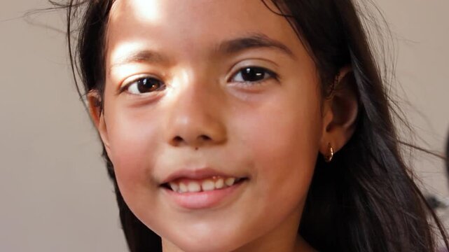 Portrait of a beautiful Colombian girl smiling and looking at the camera against a wall inside a house in Neiva, Huila, Colombia. Concept of childhood and happiness