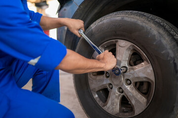 Mechanic changing car tire using lug wrench