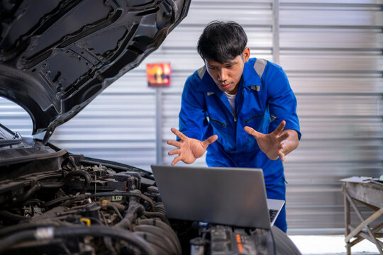 Asian mechanic diagnosing car engine problem using laptop