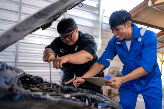 Mechanics team checking car engine, discussing maintenance schedule