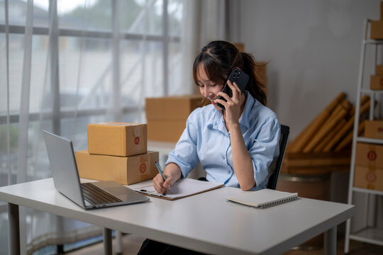 Online seller taking orders on phone and writing on clipboard