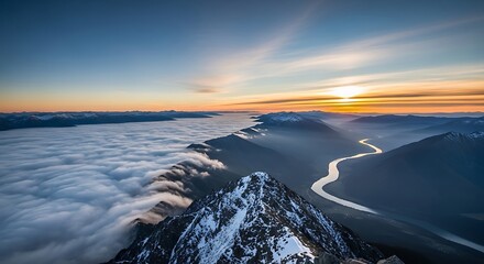 Mountain peak above clouds at sunset with river flowing through valley below