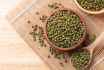 Mung bean in wooden bowl and spoon on burlap fabric background, Asian food ingredient, Top view