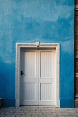Fototapeta premium Portrait of white door on blue wall background, beautiful architecture aesthetic concept