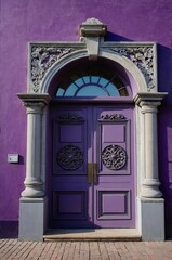 Fototapeta premium Portrait of gray door on purple wall background, beautiful architecture aesthetic concept