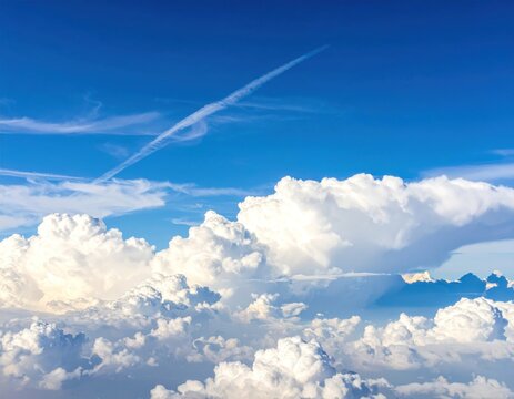 Vast blue sky filled with fluffy white clouds, airplane contrail trails