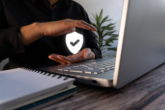 Online security. Woman working on a computer, while protecting a shield with a checkmark with her hands.