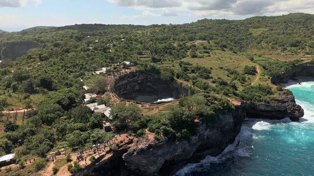 Scenic aerial view of tourists at Broken Beach, a collapsed sea cave on Bali's coast.