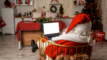 Santa Claus relaxing with a laptop in a festive Christmas decorated kitchen