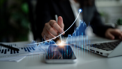 A business professional studies data trends on a smartphone while typing on a laptop, featuring...