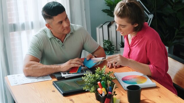 Professional happy interior designer looking at tablet while project manager choosing color palettes. Top view of smart graphic designing and looking at logo. Skilled team choosing graphic. Symposium. - Powered by Adobe