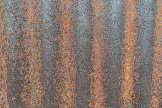Close up of a rusty corrugated metal sheet. Old zinc roofing texture with orange and brown rust patterns. Abstract grunge background. - Powered by Adobe