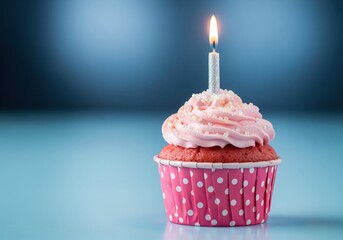Charming pink birthday cupcake with a lit candle and polka dot wrapper