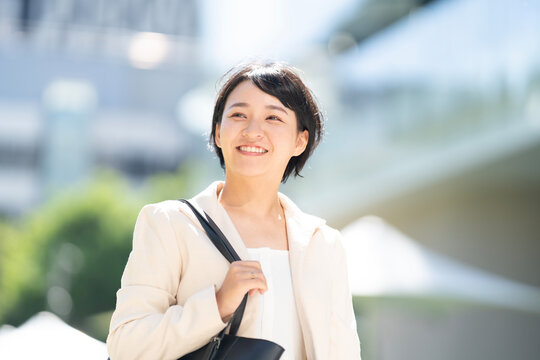 ビルをバックにスーツ姿で笑っている女性