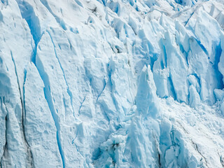 Majestic Perito Moreno Glacier with snow-capped mountains in Patagonia, Argentina. Vivid blue tones of the ice contrast with the dark slopes, highlighting the raw beauty of nature.