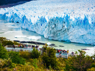 Majestic Perito Moreno Glacier with snow-capped mountains in Patagonia, Argentina. Vivid blue tones of the ice contrast with the dark slopes, highlighting the raw beauty of nature.