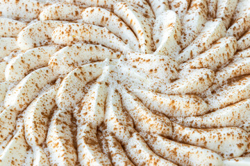 detail of a topping of a cake or pie with cream and cinnamon, cream pattern background