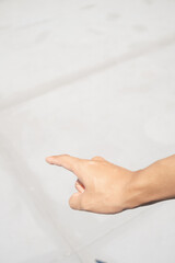A person's hand with a finger extended, pointing towards a light-colored surface.