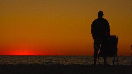 silhouette of a man sitting on the beach